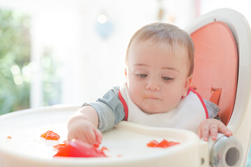 Baby boy eating gelatin dessert in high chair