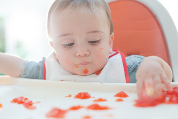 Baby boy eating gelatin dessert in high chair