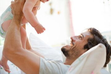 Obraz na płótnie Canvas Father playing with baby son on sofa