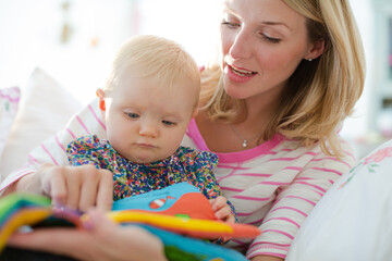 Mother reading to baby girl on sofa