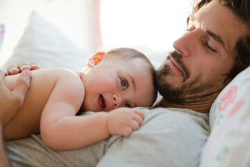 Father laying with baby boy on bed