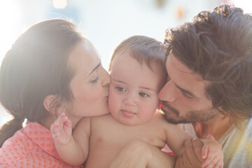 Parents kissing baby boy's cheeks