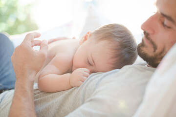 Obraz na płótnie Canvas Father laying with baby boy on bed