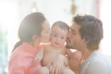 Parents kissing baby boy's cheeks