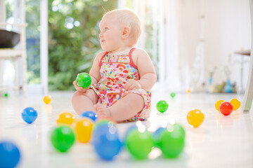 Fototapeta na wymiar Baby girl playing with toys on floor
