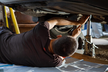 An auto mechanic works in a garage. Car repair