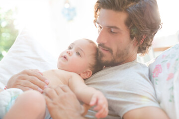 Father laying with baby boy on bed