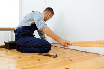 To make repairs. Installing a new skirting board. a man makes repairs in a room