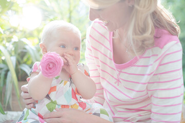 Mother and baby girl playing with flower