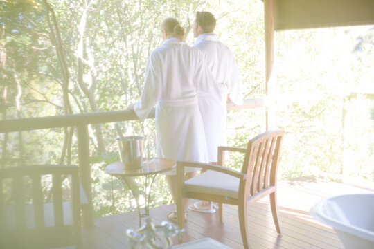 Couple in bathrobes standing on balcony