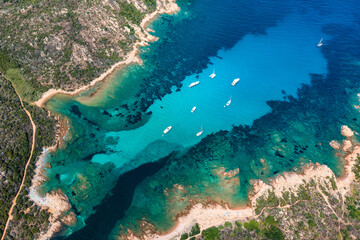 View from above, stunning aerial view of some boats and luxury yachts floating on a turquoise, crystal clear water during a sunny day.Sardinia, Italy.