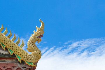 Fototapeta na wymiar Beautiful golden serpent or naga on art roof of buddhist temple, Gable of the Thai Northern art style, Buddhist temple with blue sky in Temple of Thailand