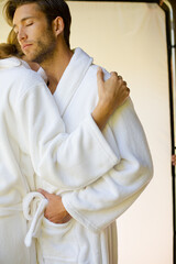 Couple in bathrobes hugging on balcony