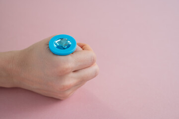 Fototapeta premium A woman is holding a blue butt plug with a crystal on a pink background. Adult toy for alternative sex