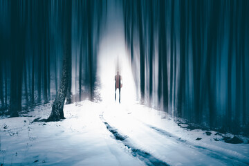Man walking alone in magical dark, foggy forest.