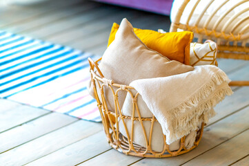 Wicker basket with blankets and pillows indoors at home. Cozy home decor.