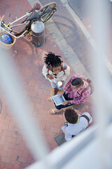 Friends using digital tablet on city street
