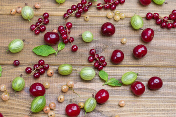 Green gooseberries, cherries  and mint leaves on table.