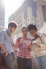 Friends using digital tablet on city street