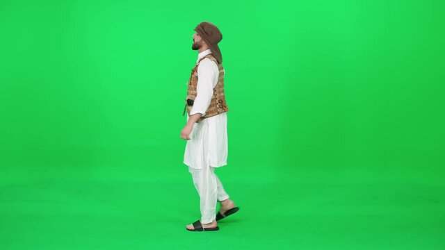 A man of Arab appearance in traditional clothes walking down the street against the green background, chromakey template.