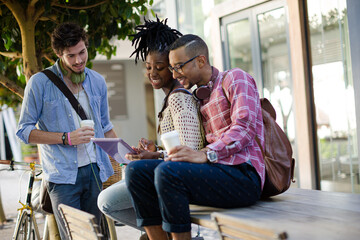 Friends using digital tablet on city street