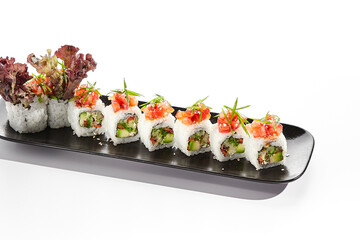 Healthy vegetarian Japanese lunch. Vegan sushi roll with avocado and mushrooms inside. Topped with tomato. Vegetarian sushi rolls dish. Restaurant asian vegan food isolated on white background.