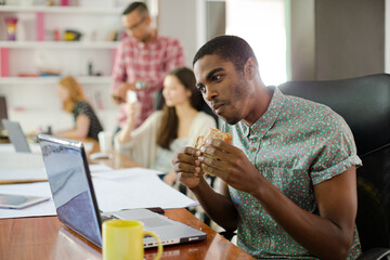 Man eating and working at conference tablet