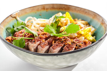 Pan asian traditional dish - fried rice with vegetables, shredded omelette and duck. Oriental wok with rice on white background. Nasi goreng with duck on isolated background with shadows.