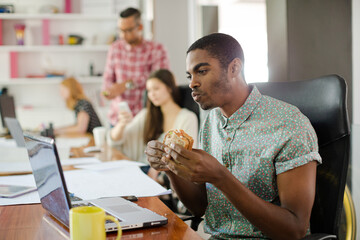 Man eating and working at conference tablet