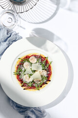 Beef carpaccio with mushrooms and parmesan cheese. Fancy dinning with beef carpaccio on white table...
