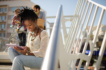 Woman using digital tablet on city street