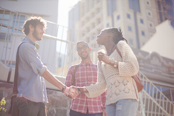 People shaking hands on city street