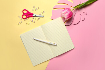 Composition with notebook, stationery and tulip on color background