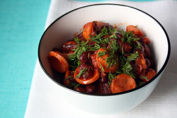 Red beans with sausages stewed in tomato paste in a white bowl.