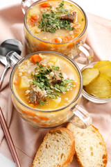 Bowls with tasty beef barley soup on white background