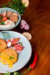 Grilled burgers with sauce and vegetable radish salad on a plate on a rustic wooden table background.