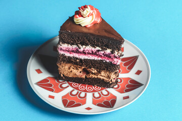 Chocolate cherry cake on a colorful plate over blue background.