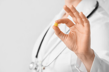 Female doctor with pill on light background