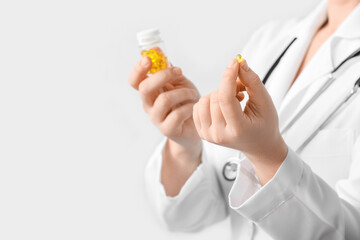 Female doctor with pill on light background