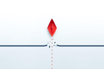 Concept of overcoming barriers, goal, target, with red paper ship breaking through obstacle on...