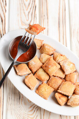 Fried dumplings stuffed with meat and served with tomato sauce on a white plate.