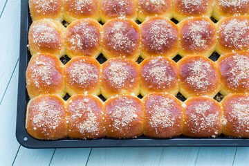 Freshly baked appetizing buns with white topping on a baking tray