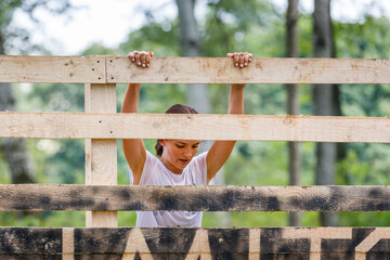 Young sportswoman climbing timber wall on her obstacle race course