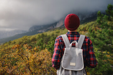Happy young woman with backpack exploring misty mountains.
