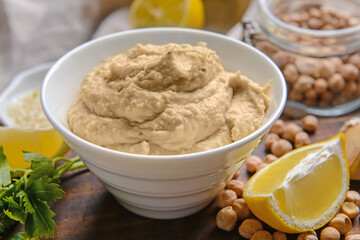 Bowl with tasty hummus and ingredients on table, closeup