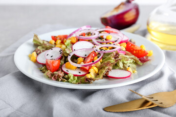 Plate of fresh salad with Lollo Rosso lettuce on table