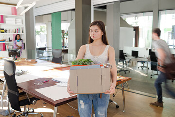 Woman carrying cardboard box in office