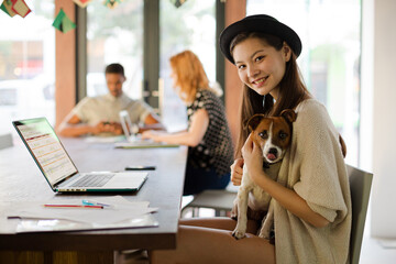 Woman holding dog and working in office
