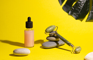 Cosmetic product in a glass bottle with a pipette and gua sha e scraper and roller. Smooth stones...