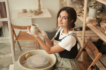Woman showing handmade clay pot in workshop